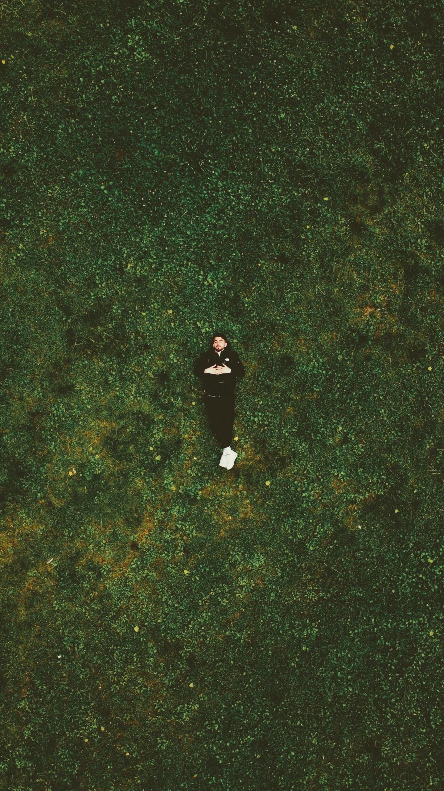 Top-down view of a person relaxing on a lush green lawn in Paris, France.